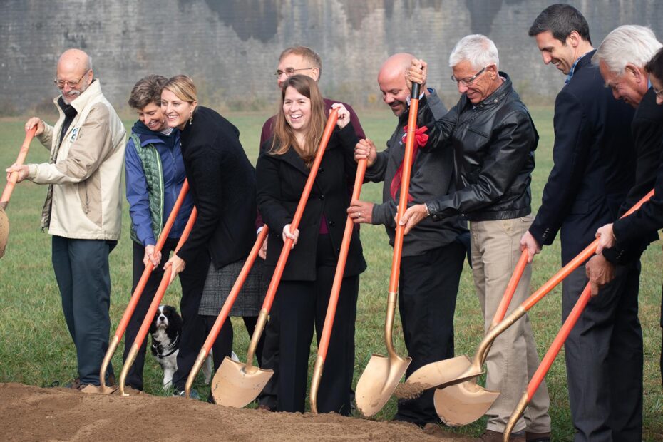 A group of people hilding shovels and smiling at a ground breaking at Tome Jones Commons
